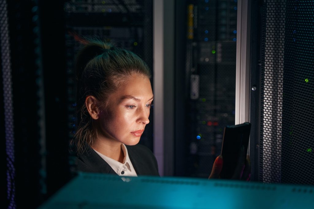 System administrator works near racks with powerful computing equipment