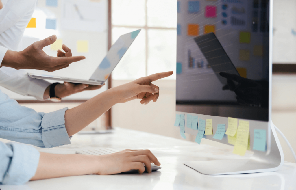 Colleagues discussing goals in front of a computer screen with sticky notes