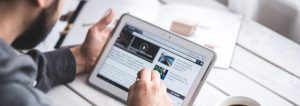 Person reading news on a tablet with a coffee nearby