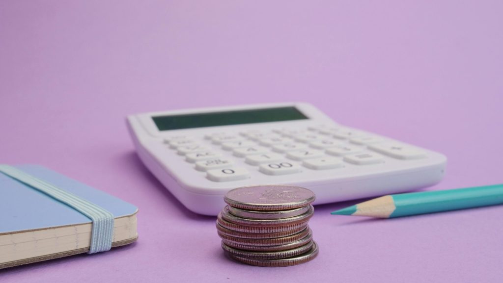 Calculator and stacked coins representing cost management