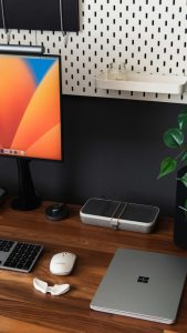 a desk with a laptop, keyboard, mouse and a monitor